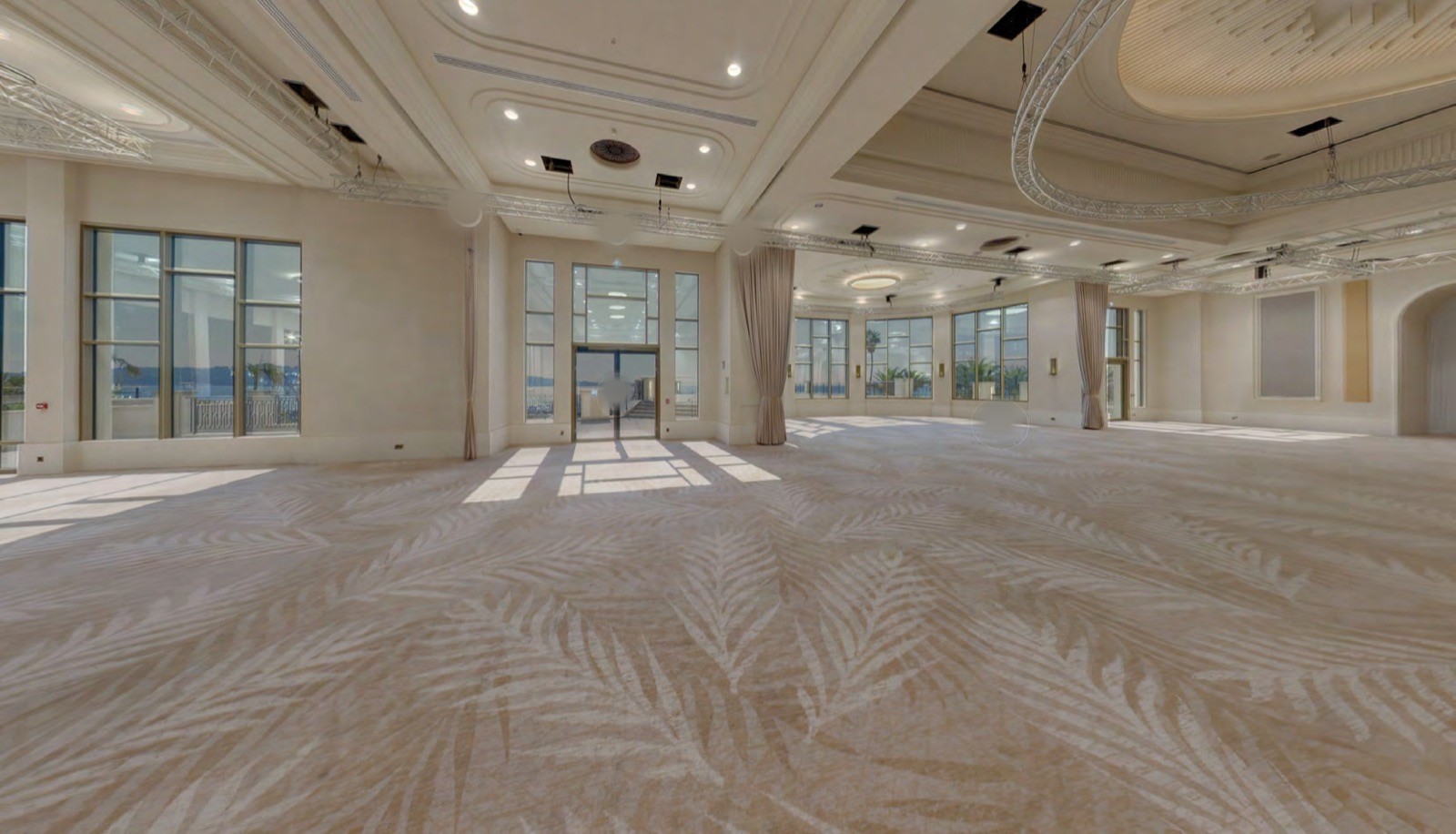 La salle Alain Delon vide, ses baies vitrées ouvertes sur la mer et son tapis à motif de palmes